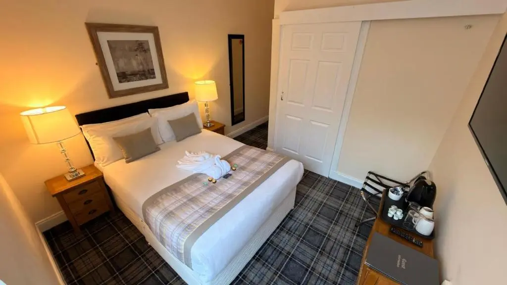 a bedroom with a large bed with two lamps at The Waverley Guest House in Inverness