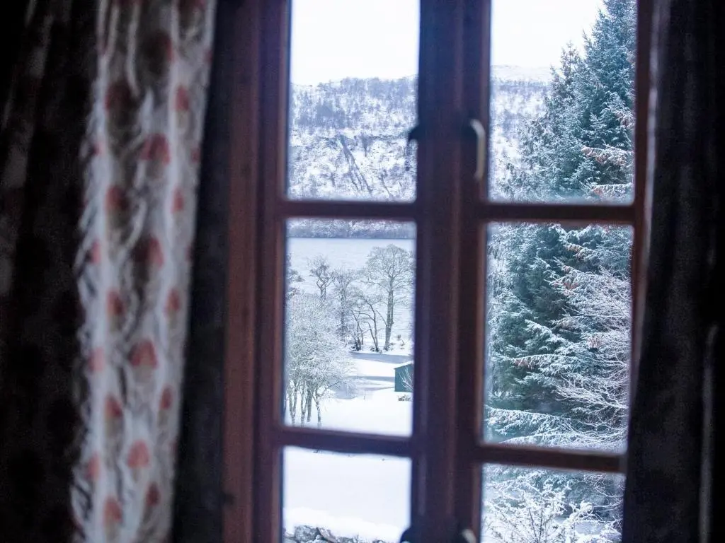 a window with a view of a snow covered yard at Holiday Home The Romantic Bothy by Interhome in Invermoriston