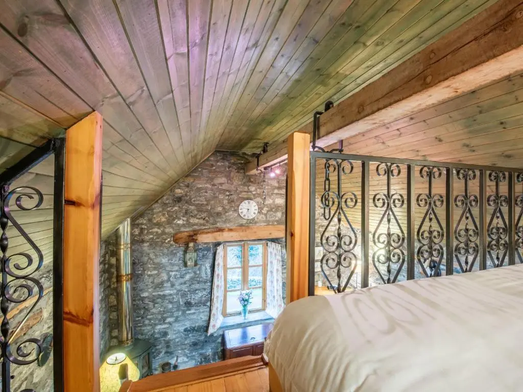 a bedroom with a bed and a stone wall at Holiday Home The Romantic Bothy by Interhome in Invermoriston
