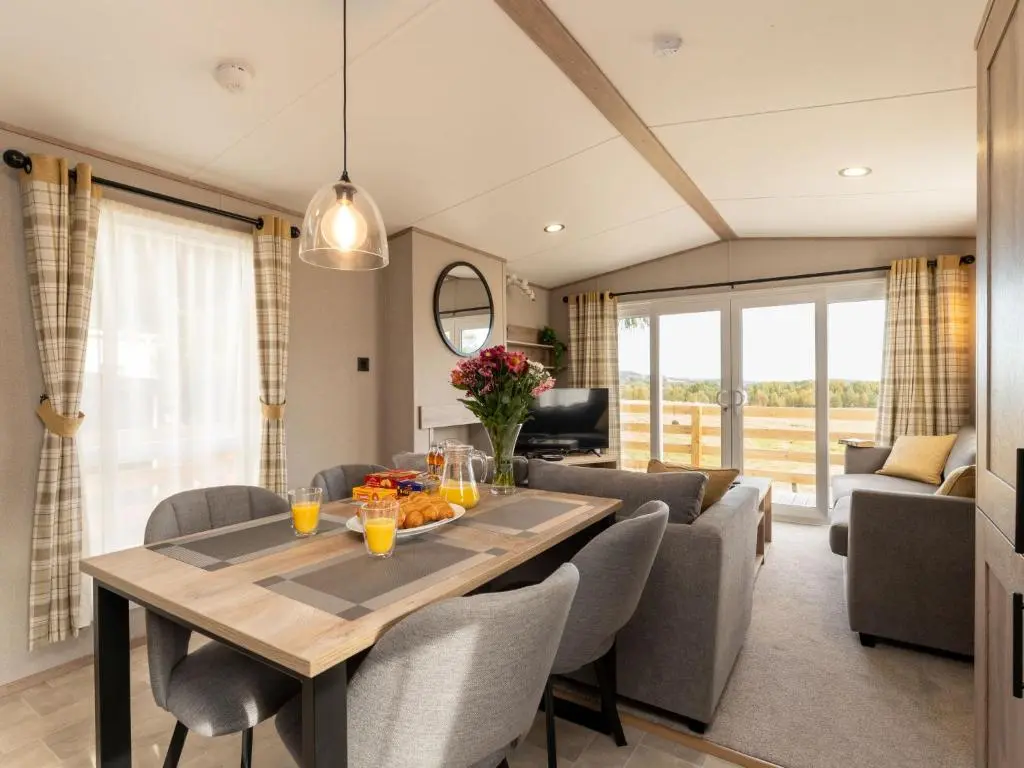 a dining room and living room with a table and chairs at Chalet Lodge 15 by Interhome in Boat of Garten