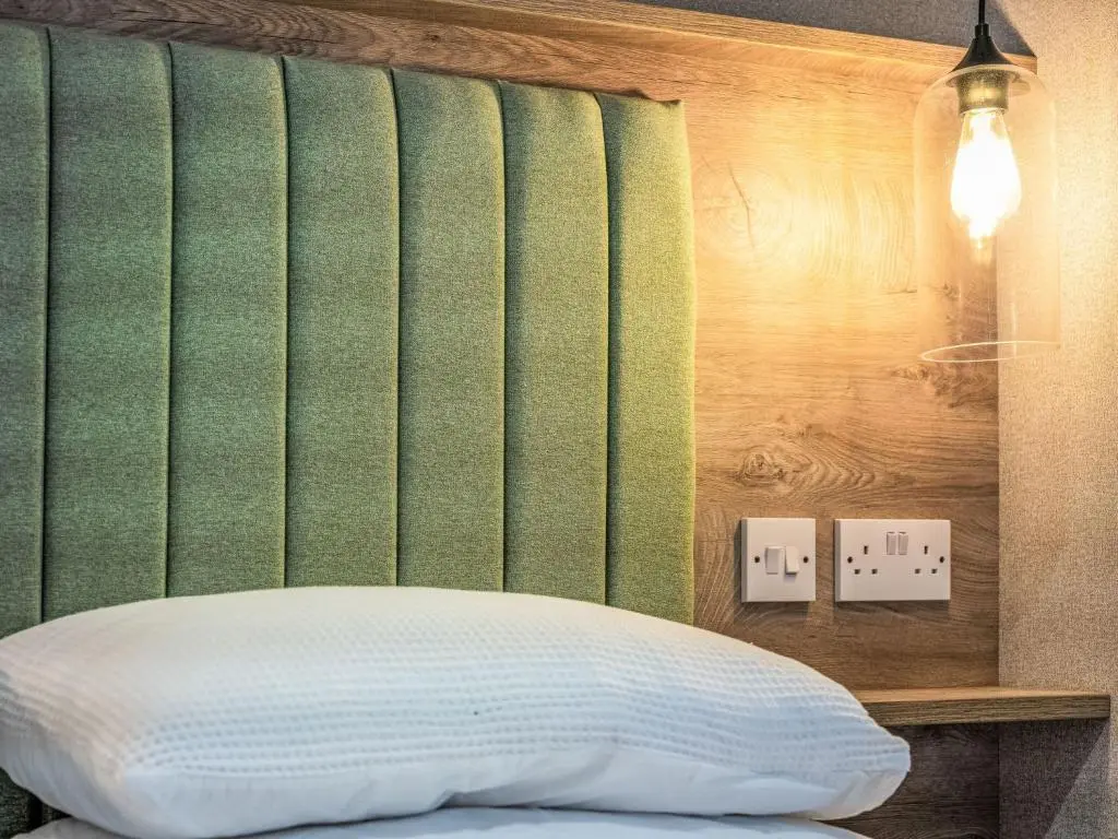 a bedroom with a green headboard and a white bed at Chalet Lodge 15 by Interhome in Boat of Garten