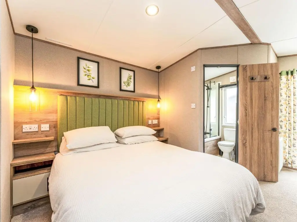 a bedroom with a large white bed and a bathroom at Chalet Lodge 15 by Interhome in Boat of Garten
