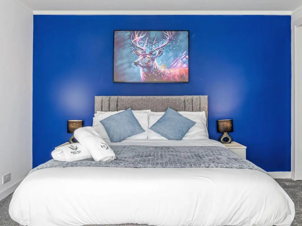 a bedroom with a blue wall with a large bed at Holiday Home Gordonstoun Cottage by Interhome in Elgin