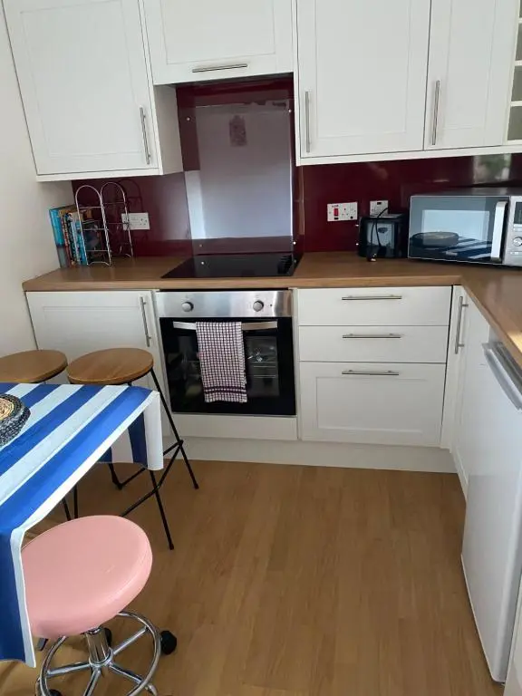a kitchen with white cabinets and a table and a microwave at Church st 48B in Inverness