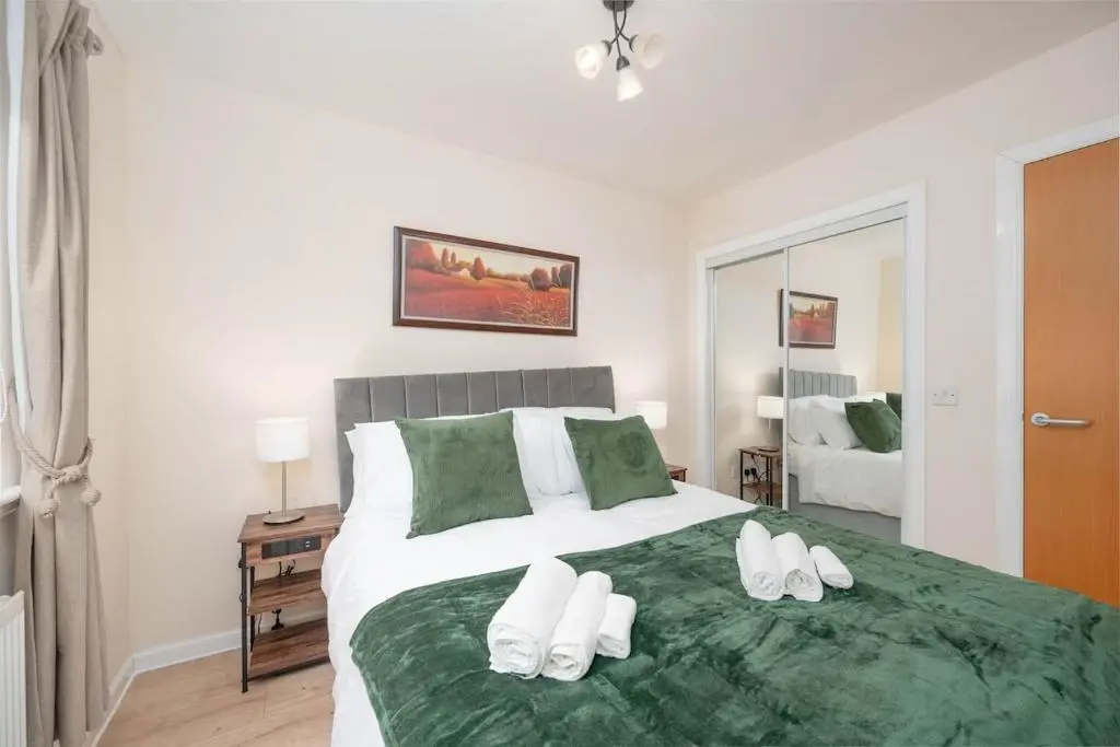 a bedroom with a large white bed with green sheets at Aberdeen 2BR Flat Near Airport & City Centre in Aberdeen