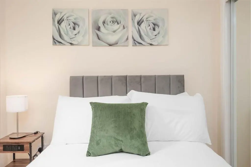 a bedroom with a white bed with two paintings on the wall at Aberdeen 2BR Flat Near Airport & City Centre in Aberdeen