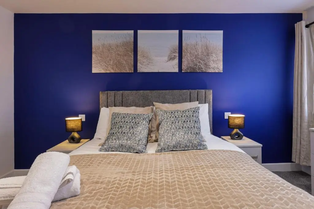 a bedroom with blue walls and a bed with two lamps at Duffus Nights in Duffus