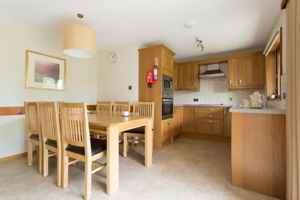 a kitchen with a wooden table and chairs at Macdonald Spey Valley Resort in Aviemore