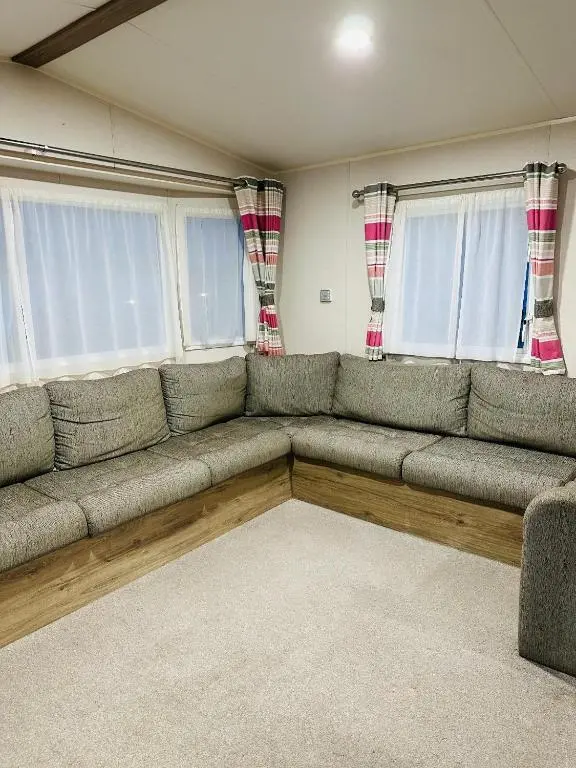 a living room with a gray couch in front of windows at Aurora Sky in Lossiemouth