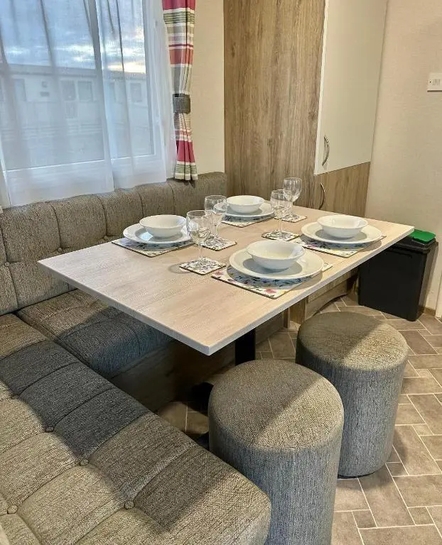 a wooden table with plates and wine glasses on it at Aurora Sky in Lossiemouth