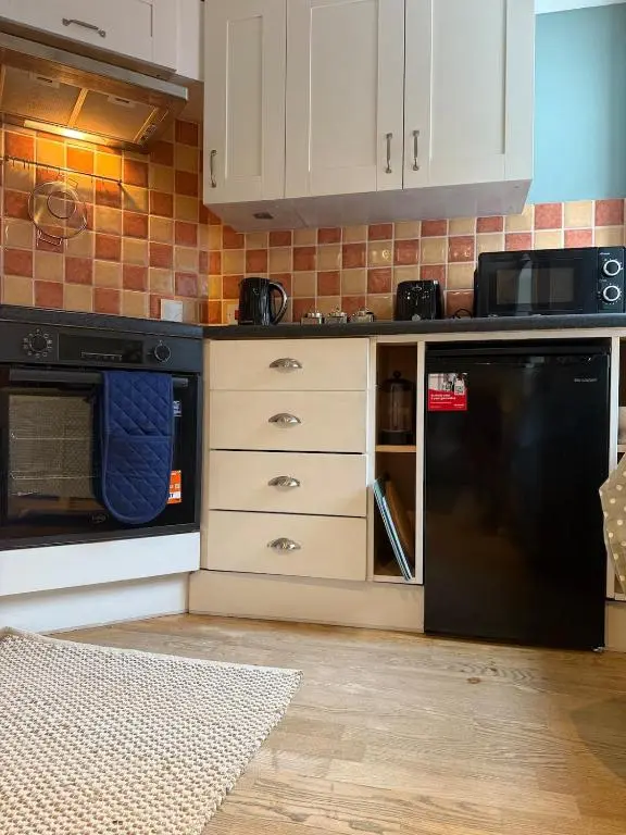 a kitchen with white cabinets and a black refrigerator at Friar's Rest - Beauly Village in Beauly