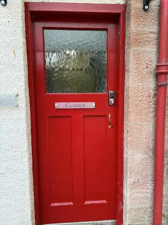 a red door with a window on a building at Cannich at RHA in Dalneigh