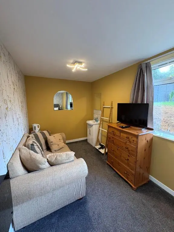 a living room with a couch and a flat screen tv at Cannich at RHA in Dalneigh