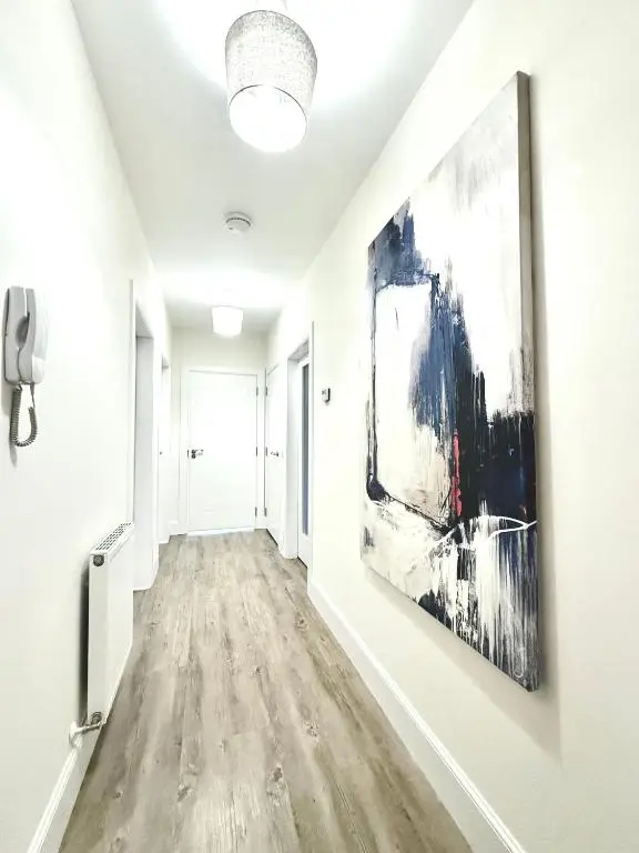 a hallway with white walls and a painting on the wall at Picturesque Tornagrain Apartment 2bed Free Parking WiFi - Near Inverness Airport