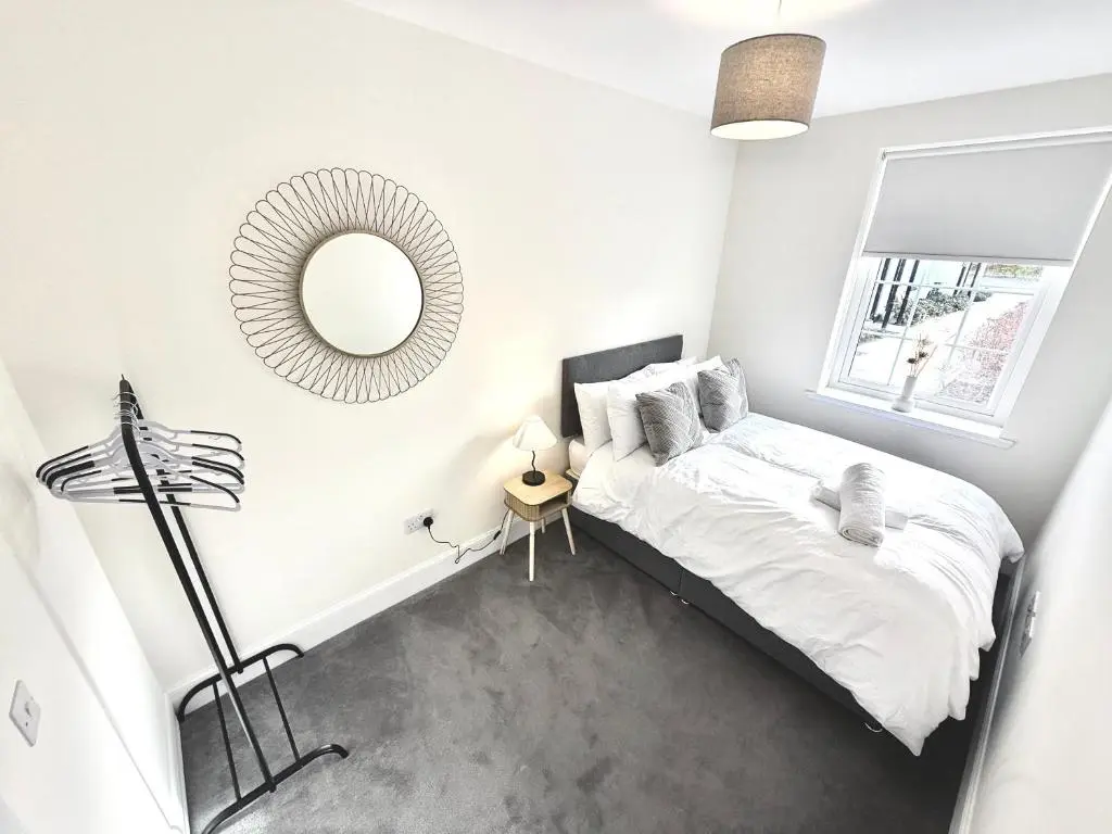 a white bedroom with a bed and a mirror at Picturesque Tornagrain Apartment 2bed Free Parking WiFi - Near Inverness Airport