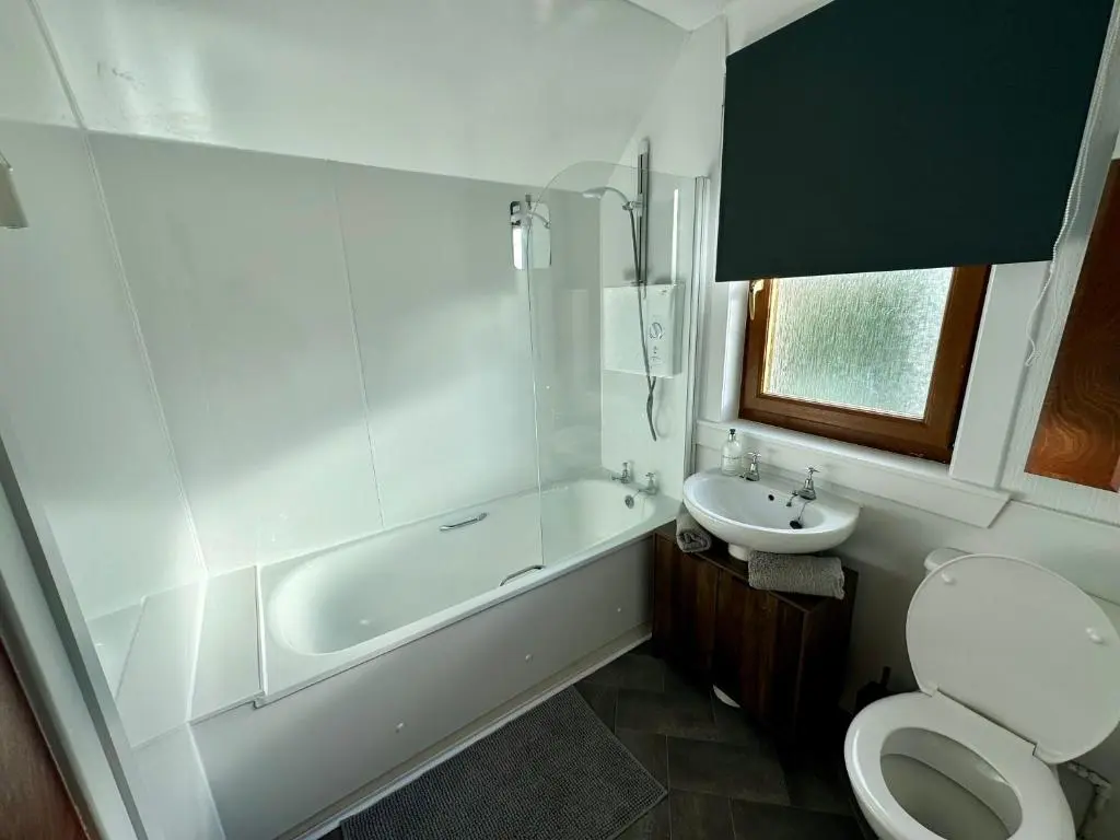 a bathroom with a toilet and a tub and a sink at Bruce Gardens Home in Inverness
