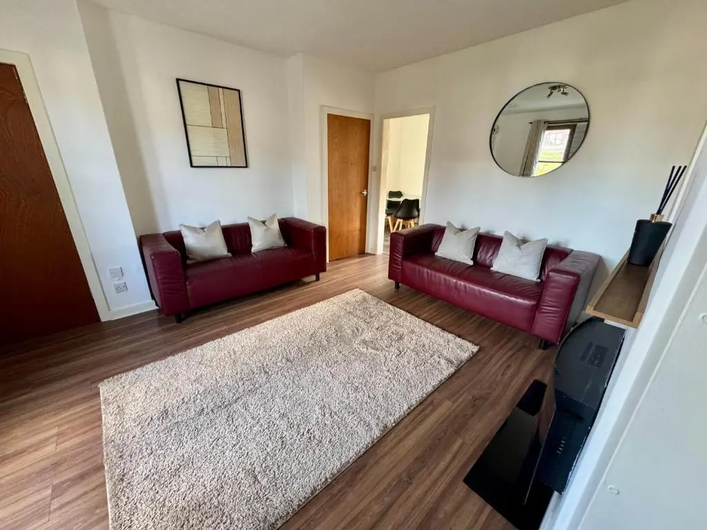 a living room with two red couches and a mirror at Bruce Gardens Home in Inverness
