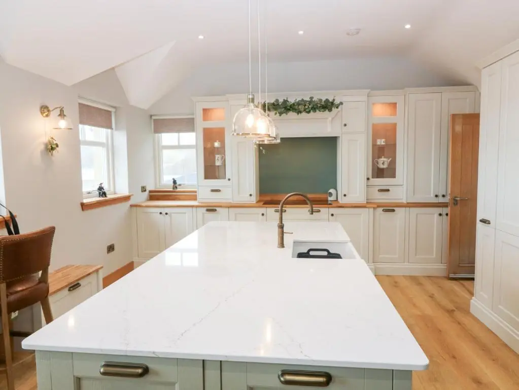 a kitchen with white cabinets and a sink at The Old Kipper Hoose in Banff