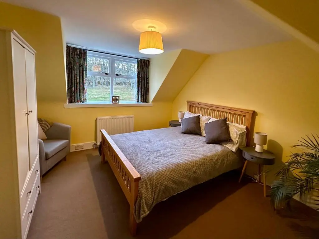 a bedroom with a large bed and a window at Cosy Cottage on the Whisky Trail in Haugh of Glass