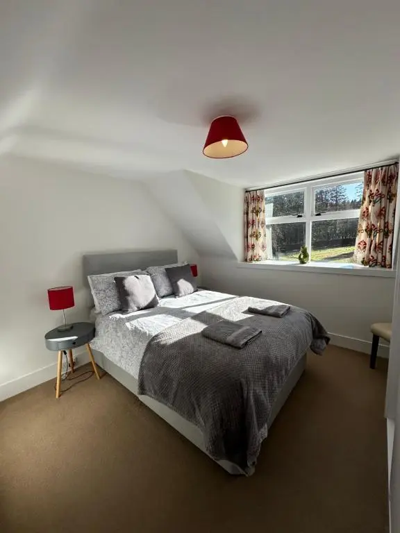 a bedroom with a bed and a red lamp at Cosy Cottage on the Whisky Trail in Haugh of Glass