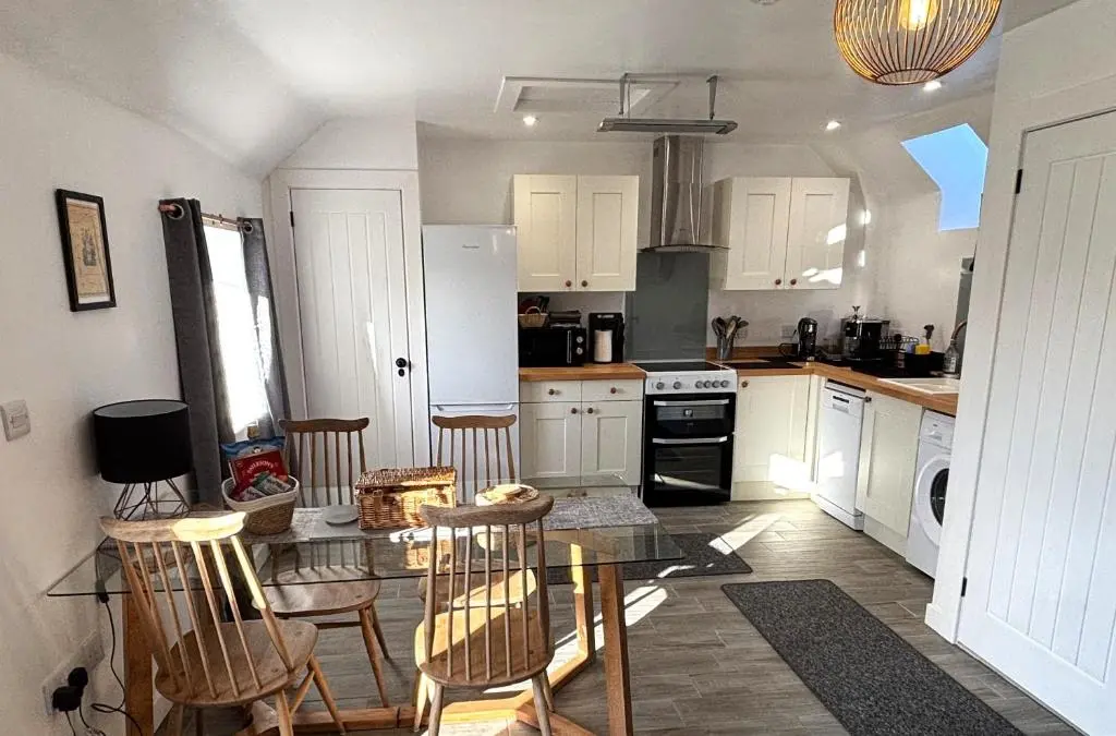 a kitchen with a table and some chairs in it at Smiddy Cottage in Portmahomack