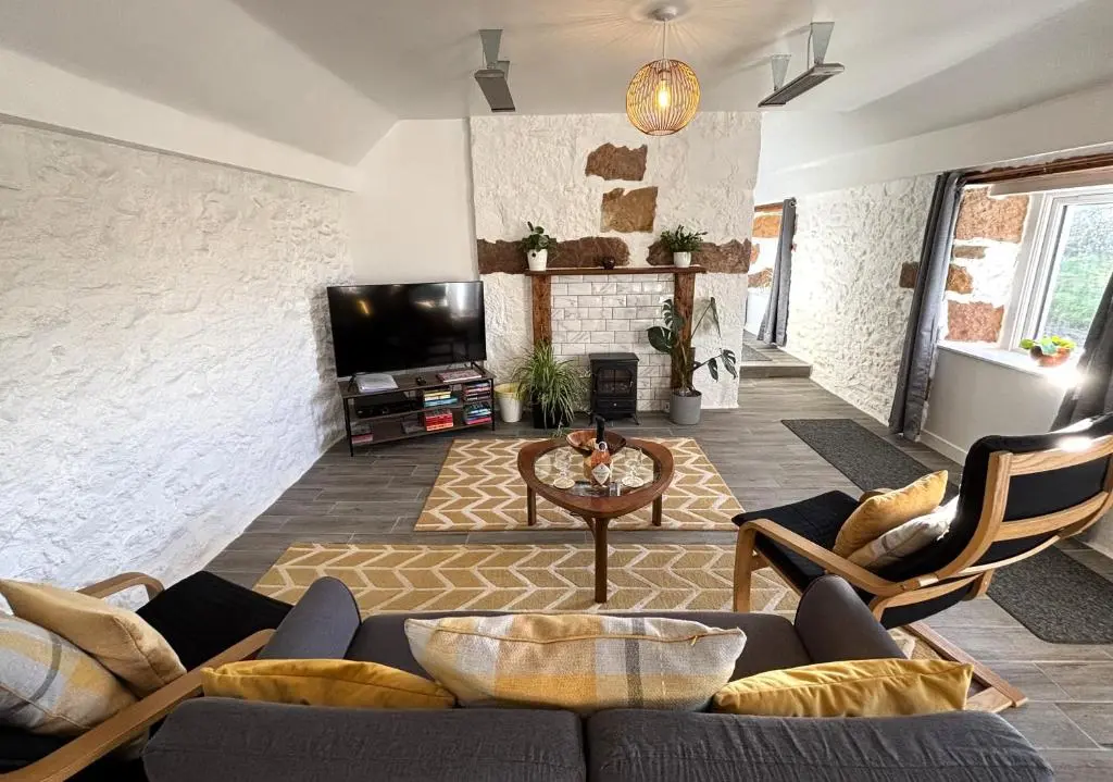 a living room with a couch and a tv at Smiddy Cottage in Portmahomack