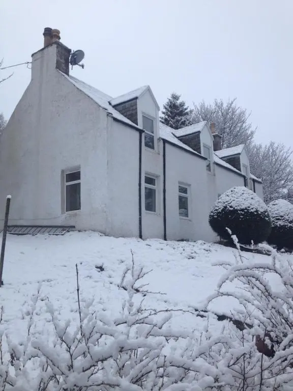 a white house with snow on the ground at Charming cottage close to the Cairngorms in Ballindalloch