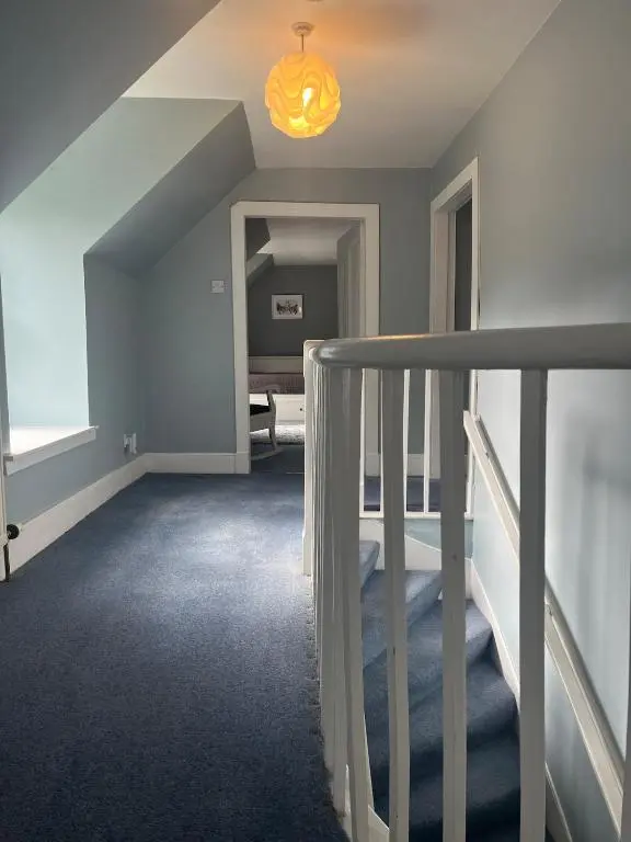 an attic room with a staircase and a bedroom at Charming cottage close to the Cairngorms in Ballindalloch