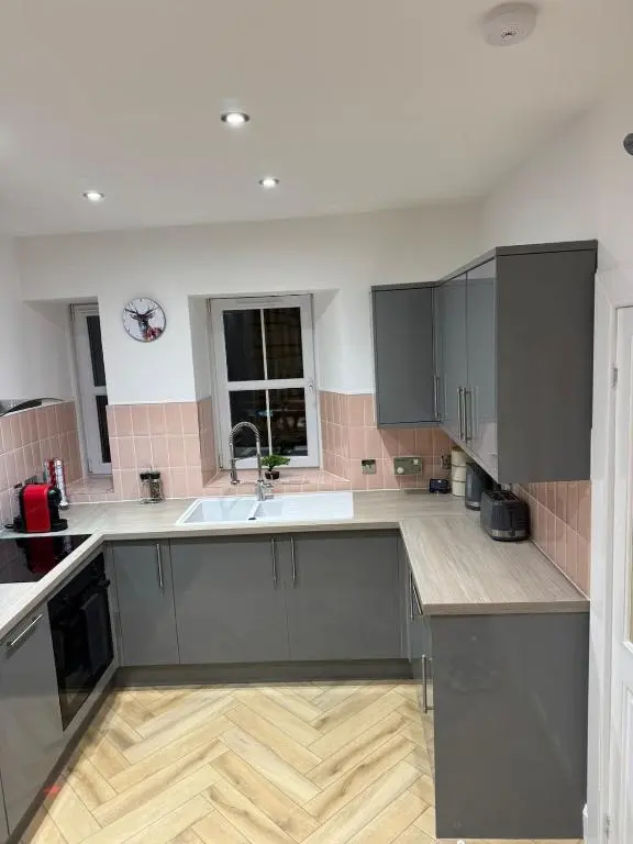 a kitchen with gray cabinets and a wooden floor at Glenburn Cottage in Kirkmichael