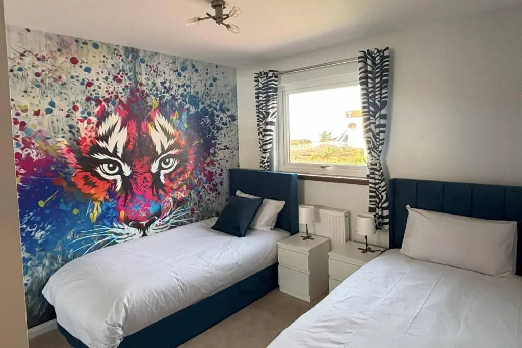 a bedroom with two beds and a painting of a peacock at The Burghead Hideaway in Burghead