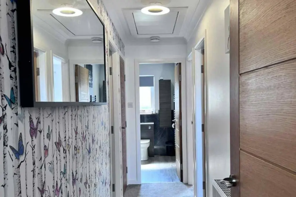 a hallway with a bathroom with a toilet and a mirror at The Burghead Hideaway in Burghead