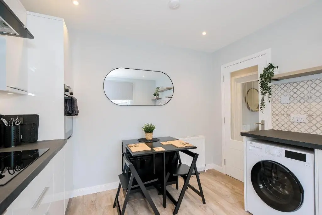 a small kitchen with a table and a washing machine at High Street Retreat in Inverurie