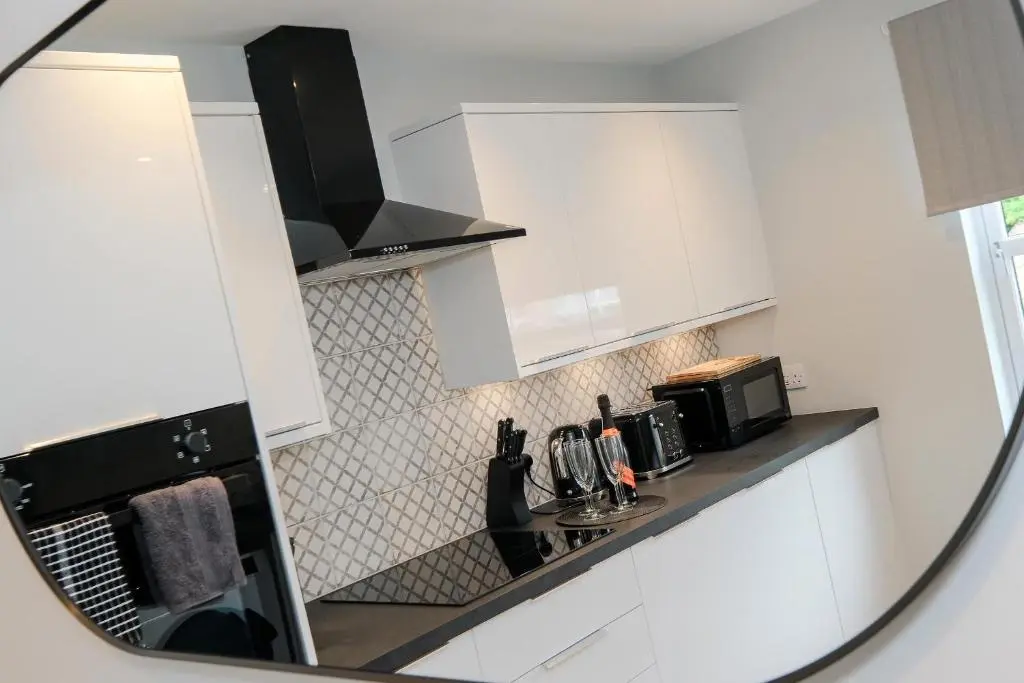 a mirror reflection of a kitchen with white cabinets at High Street Retreat in Inverurie