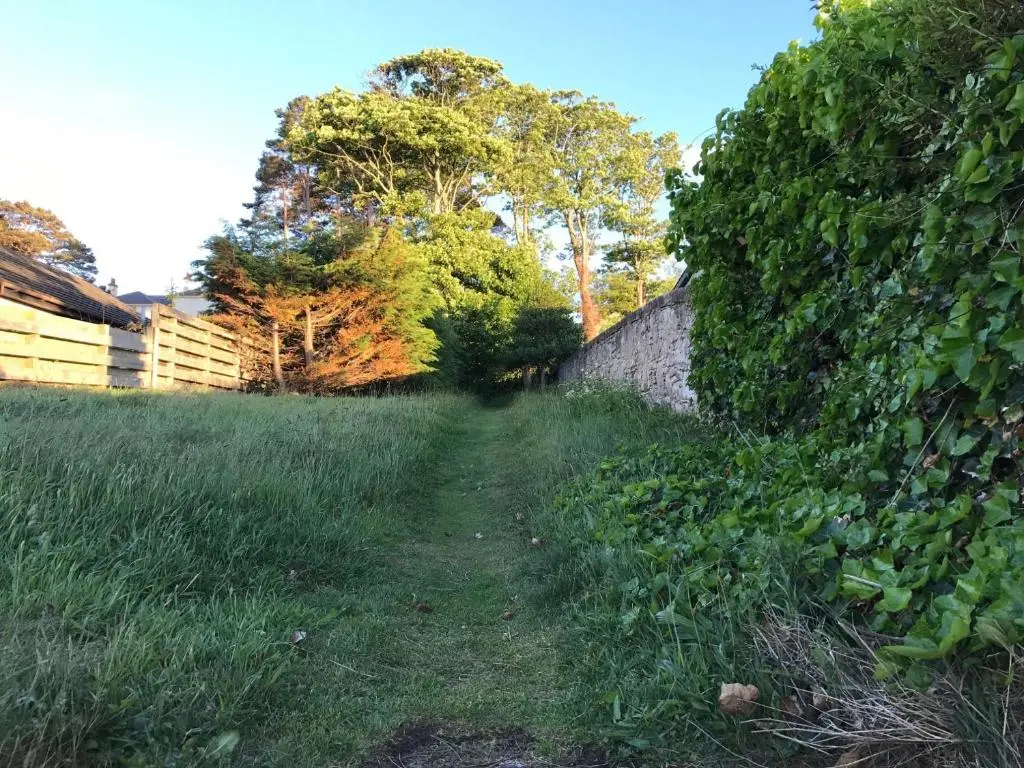a path in a field next to a fence at The Bunker Self Catering in Nairn