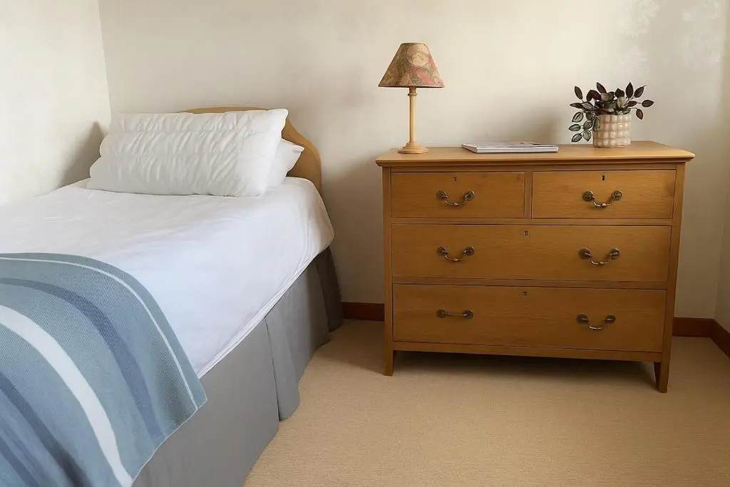 a bedroom with a bed and a dresser with a lamp at Beachy Days and Family Stays in Nairn