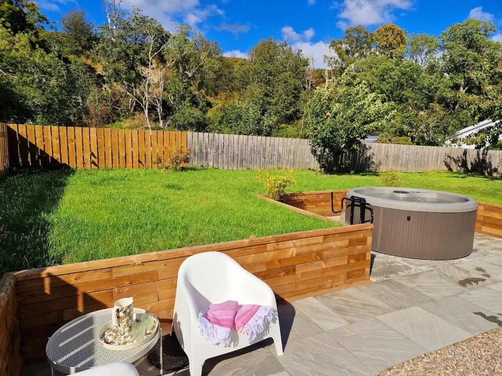 a patio with a white chair and a table at Highland River Cottage with Hot Tub in Evanton