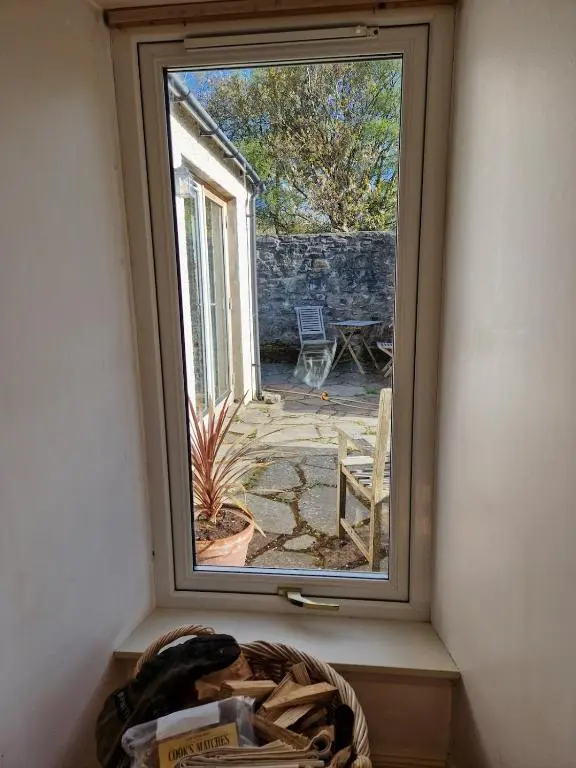 a window in a room with a view of a patio at Highland River Cottage with Hot Tub in Evanton