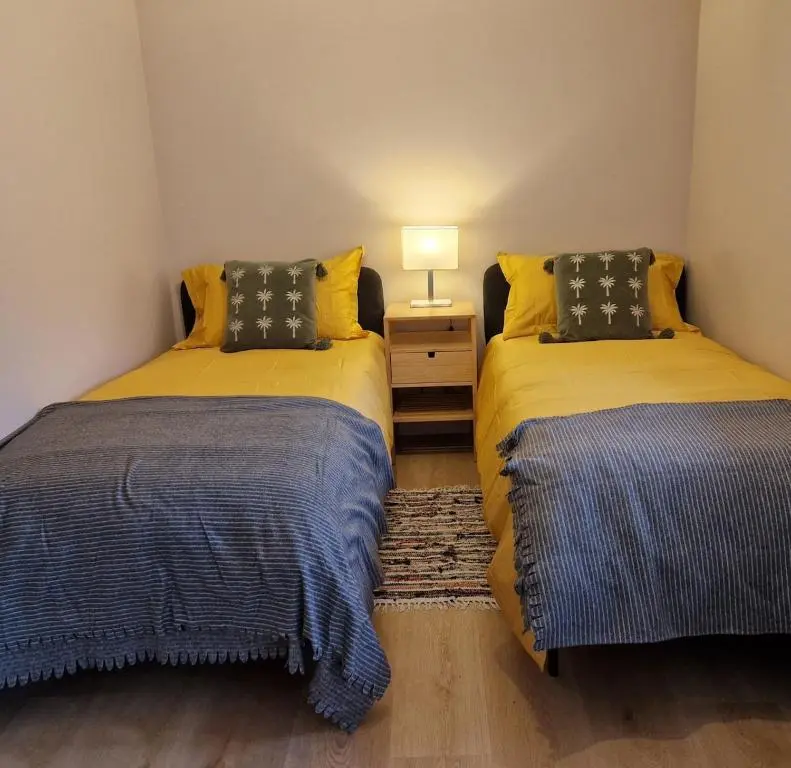 two beds in a small room with a lamp on a table at Highland River Cottage with Hot Tub in Evanton