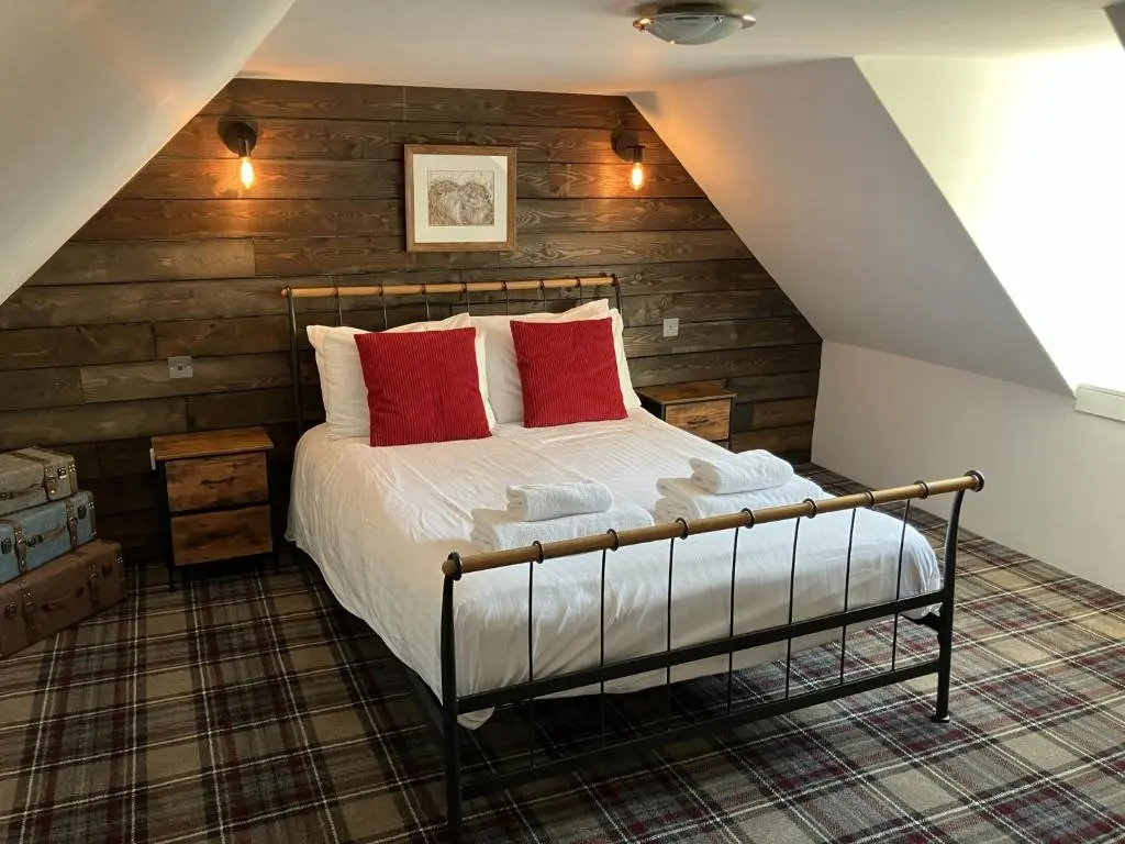 a bedroom with a bed with red pillows at Culrain Cottage in Fort Augustus