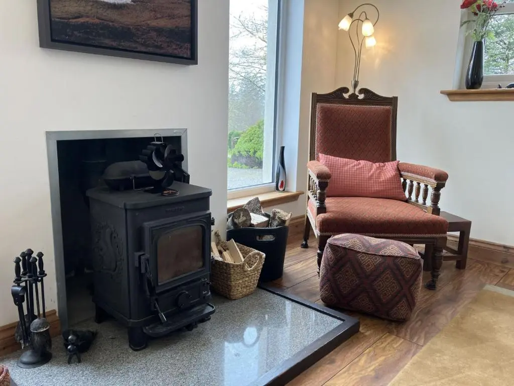 a living room with a stove and a chair at Oiseval in Fort Augustus