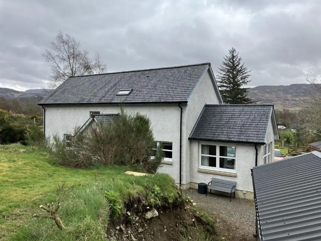 a white house with a bench in front of it at Oiseval in Fort Augustus