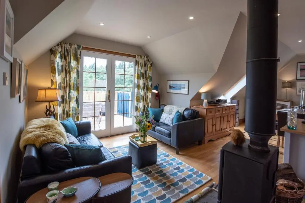 a living room with a couch and a stove at Beautiful dog friendly lodge with hot tub in Aboyne