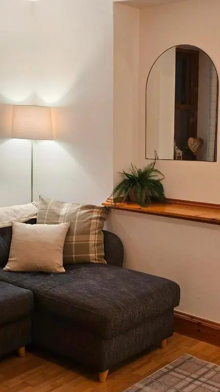 a living room with a couch and a mirror at The Saddlery Inverness in Dalneigh