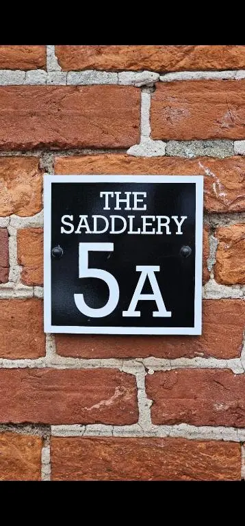 a sign on the side of a brick wall at The Saddlery Inverness in Dalneigh