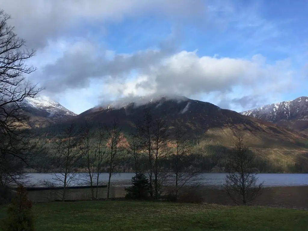 a mountain in the distance with a lake and trees at Mountain Thyme Lodge in Kilfinnan