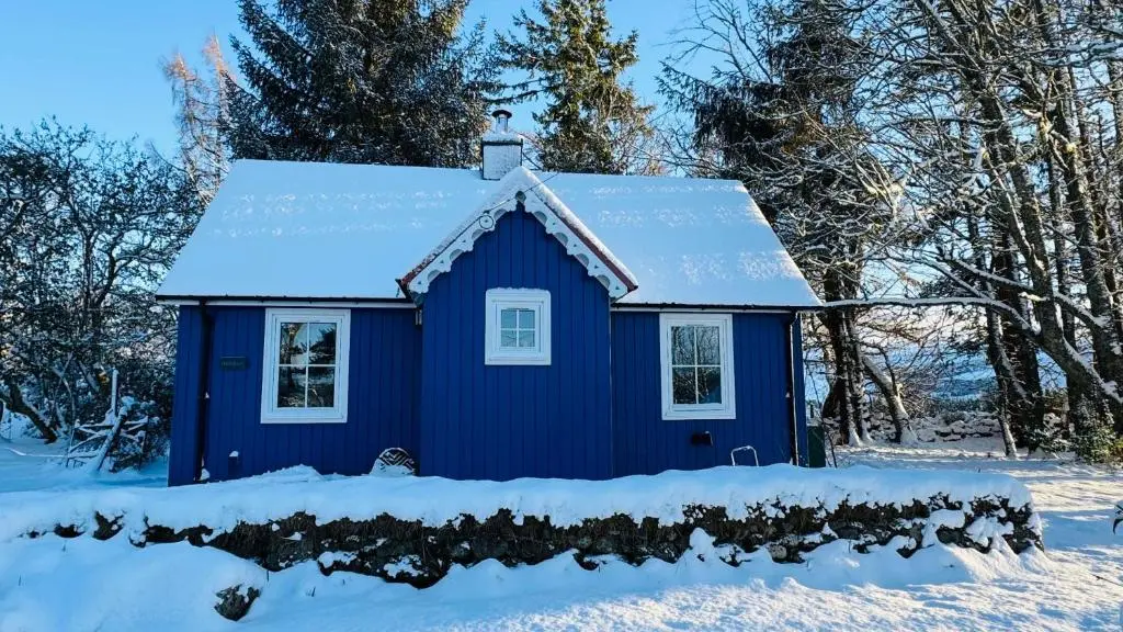 a blue house with snow on the roof at Ardshiel in Foyers