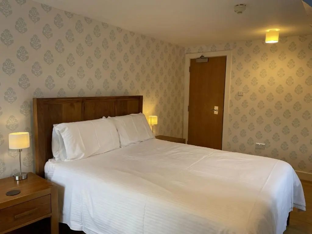 a bedroom with a white bed and a wooden headboard at Moat House 6 in Fort Augustus