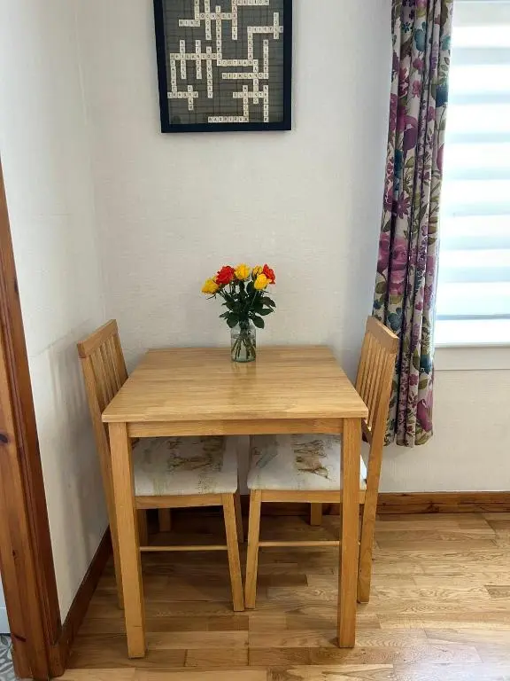 a table with two chairs and a vase of flowers on it at Cosy 1 bedroom ground floor flat, Central Inverness in Inverness