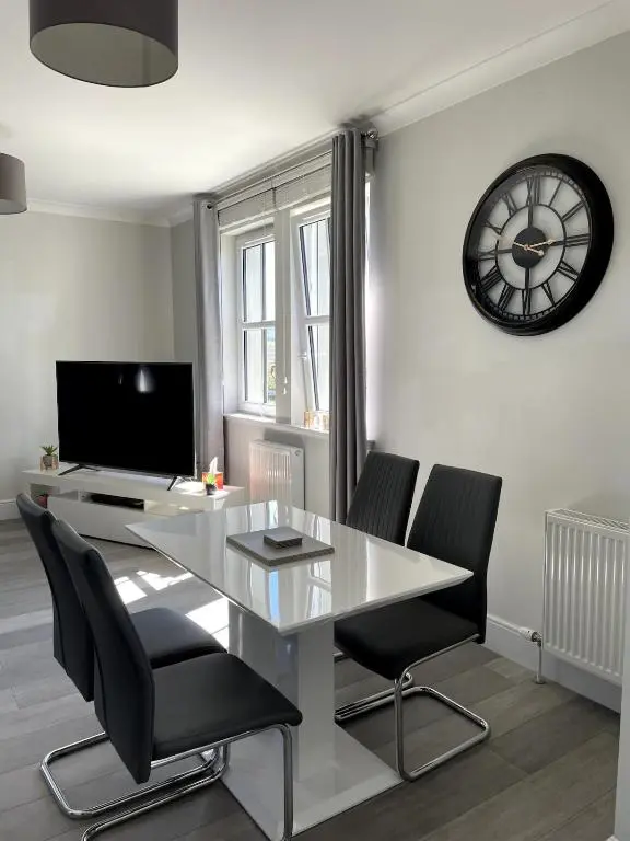 a dining room with a table and chairs and a clock at Spacious Flat in Aberdeenshire in Insch