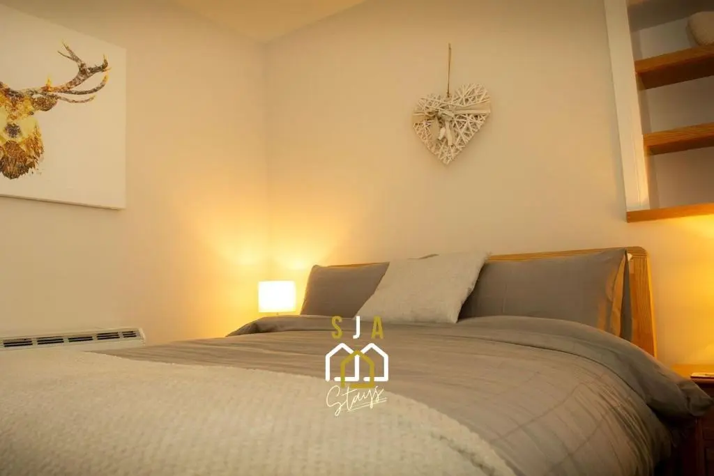 a bedroom with a bed with a heart on the wall at Beachside Cottage - SJA Stays - Modern 3 Bedroom House in Cullen